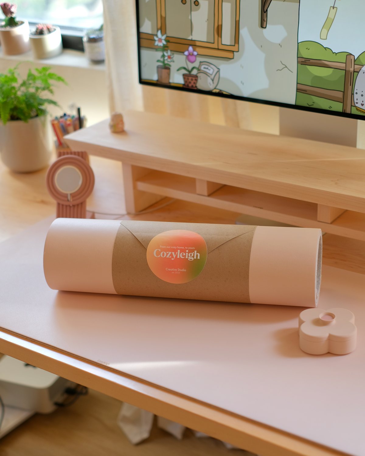 A Blush Cozyleigh Desk Mat rolled up on the desk, with a Fa Trinket Tray beside it