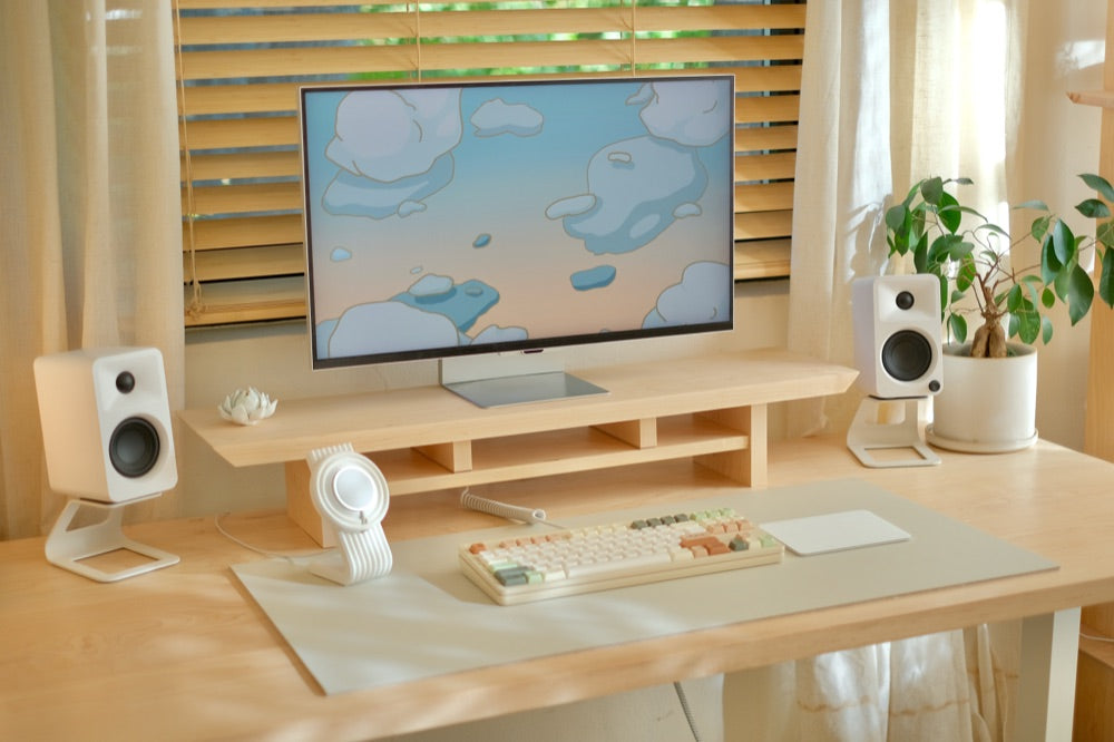 A monitor on a maple desk shelf showing the cloud wallpaper