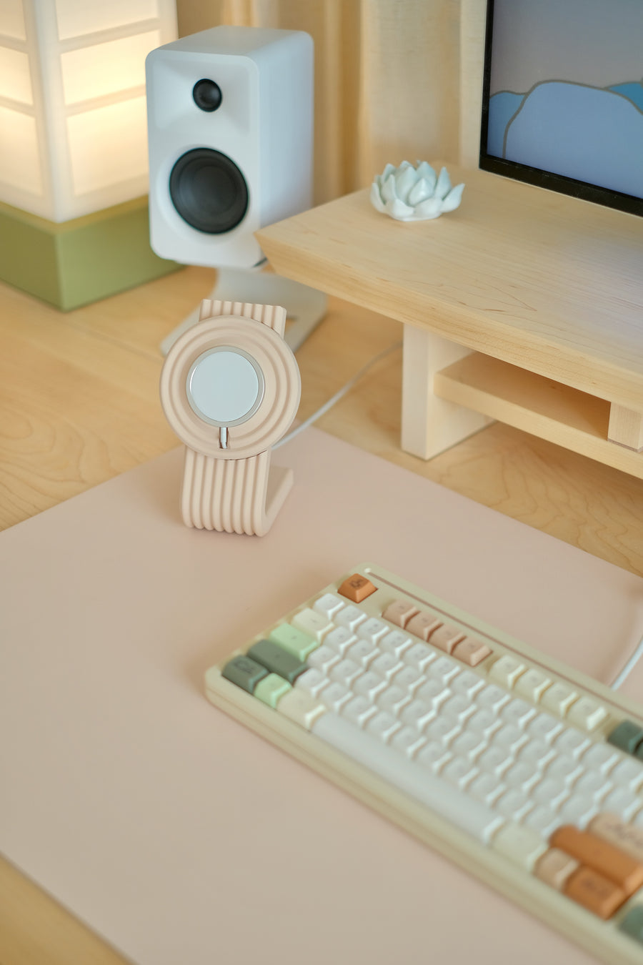 A Blush desk mat with a keyboard and a Dusty Blush Charger Stand at the studio desk