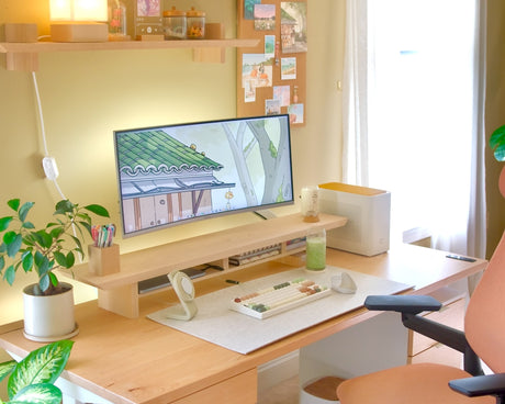 Desk setup with a Cozyleigh Desk Mat under a keyboard and a maple Zen Desk Shelf raising a monitor