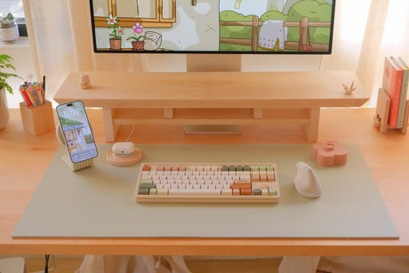 Cozyleigh Desk Mat in Matcha on a maple desk under a Zen Desk Shelf, with a keyboard, mouse and Zen MagSafe Charger Stand (Large mat shown)