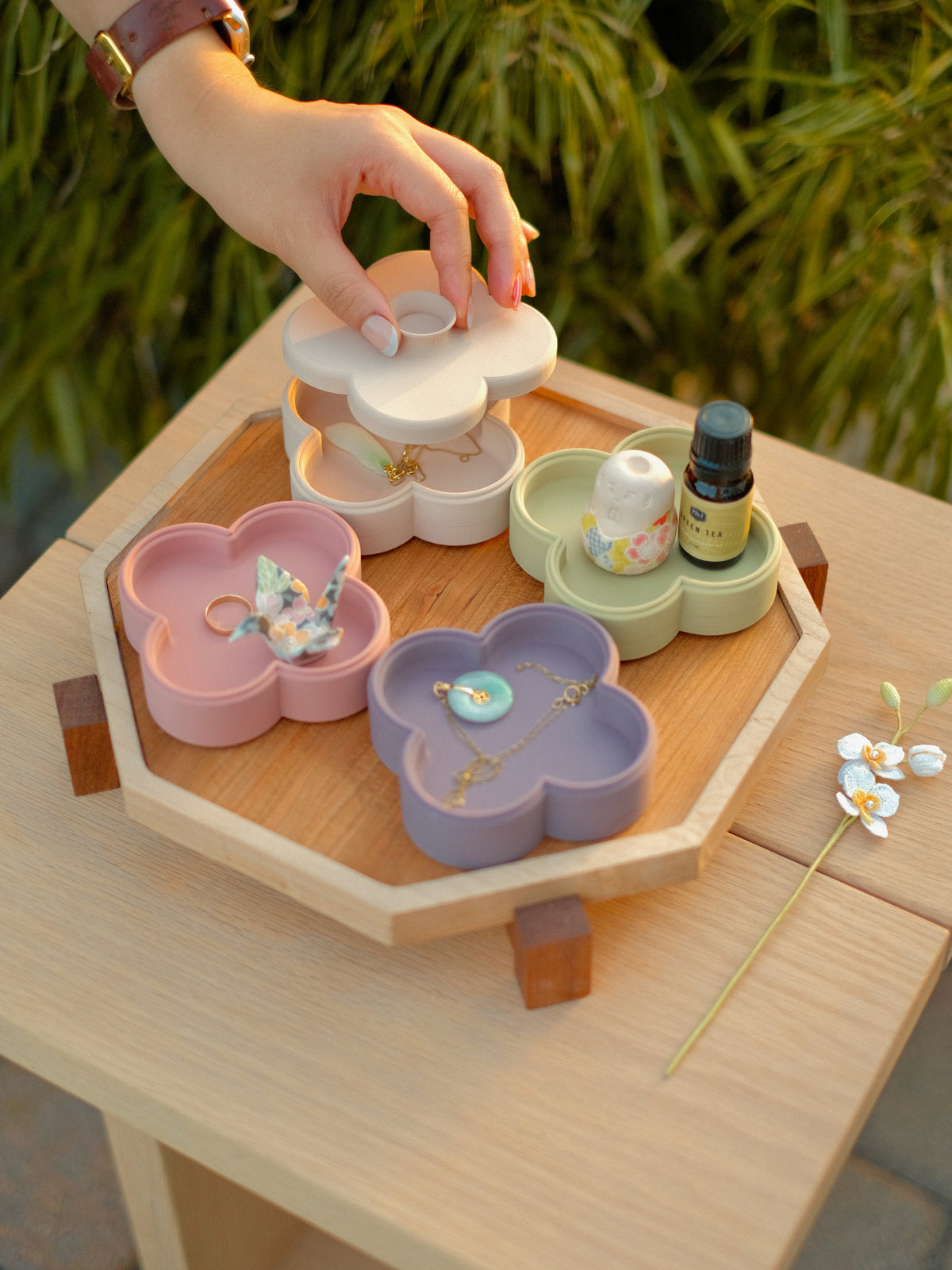 Hand lifting the lid off a Fa Trinket Tray, with Rose, Pistachio and lilac trays on a Zen Tray