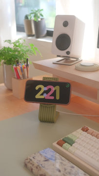 Coming this fall: a hand sets an iPhone on the Zen MagSafe Charger Stand in Moss, and the phone turns into a clock while it charges