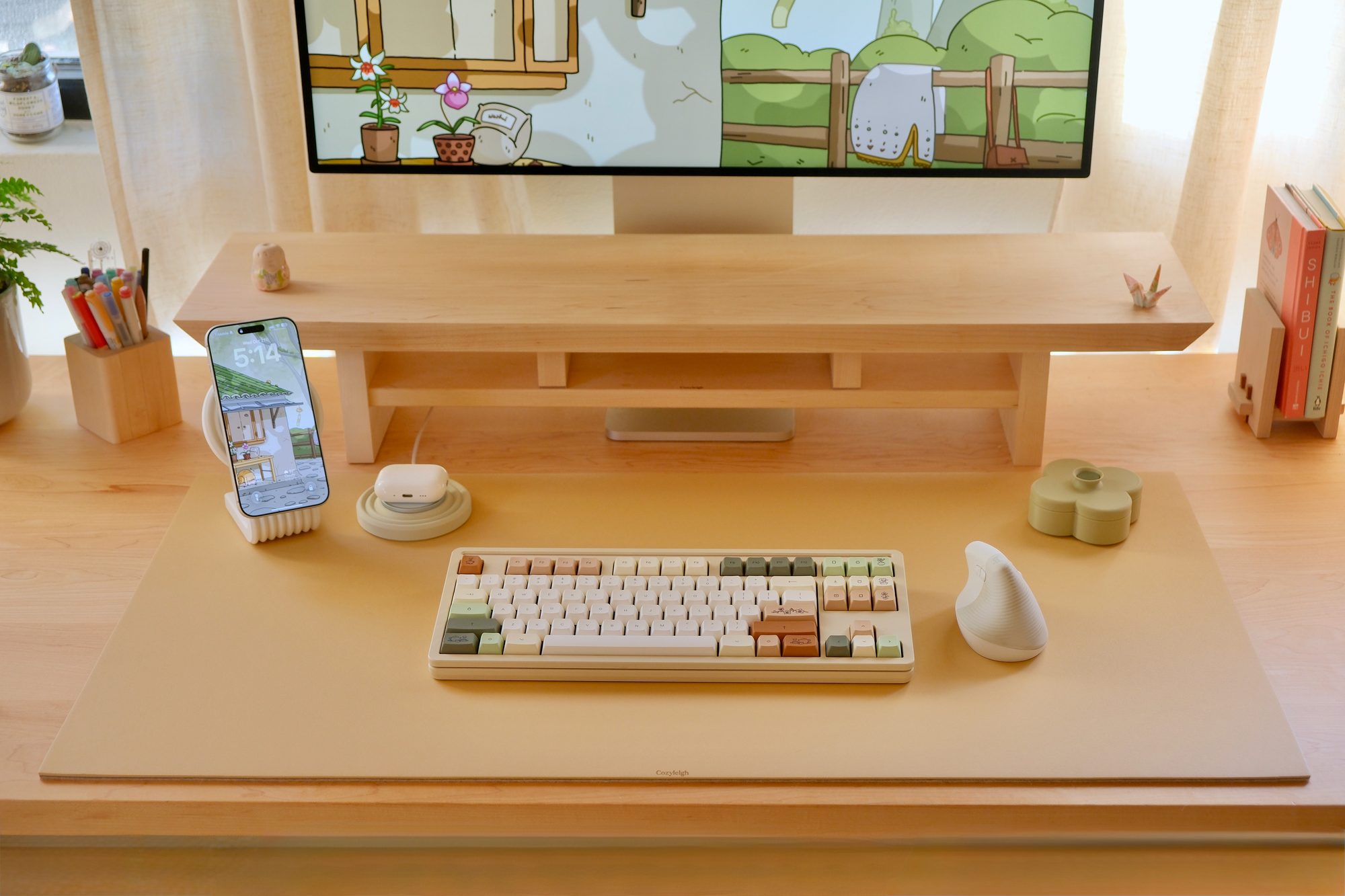 A Latte Cozyleigh Desk Mat with a White Zen MagSafe Charger Stand and a Pistachio Fa Trinket Tray, with a phone and AirPods on the stand